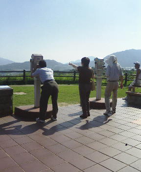 望遠鏡で厳島神社を探す三人