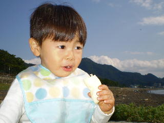 海を見ながらリンゴをほおばる幼児