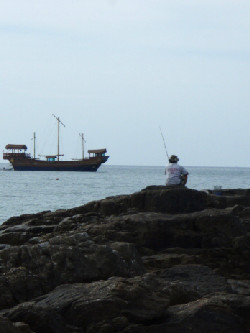 岩の上で釣りをしているおじさん